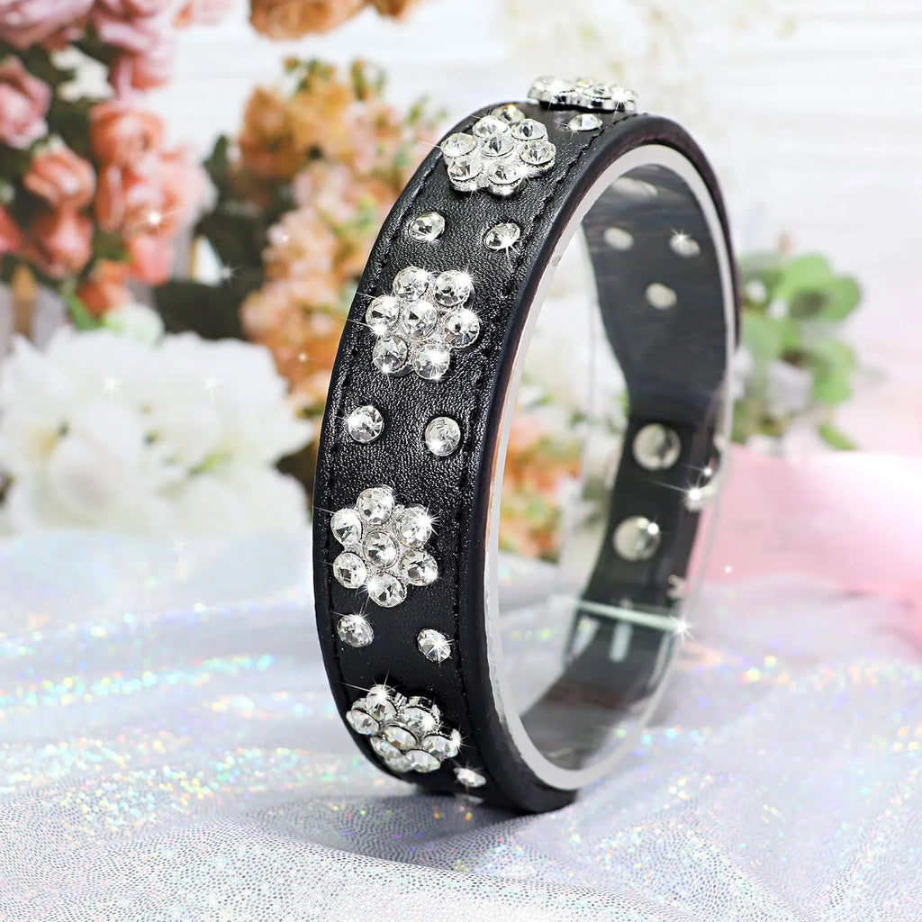 Close-up of a black PU leather dog collar with a sparkling rhinestone flower pattern and silver studs.