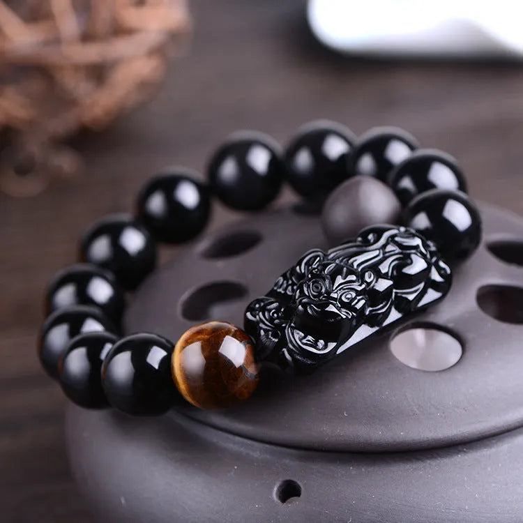 Natural obsidian carved Pi Xiu bracelet with black beads on a cord, gift box and bag visible