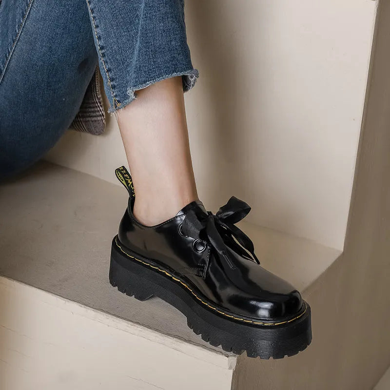 Women's thick-soled black shoes with cross strap and ribbon detail, lace-up closure