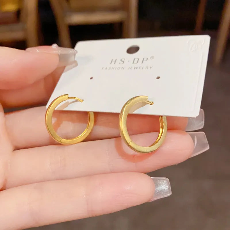A pair of geometric round eyelet ear clips for women in gold or silver plating.