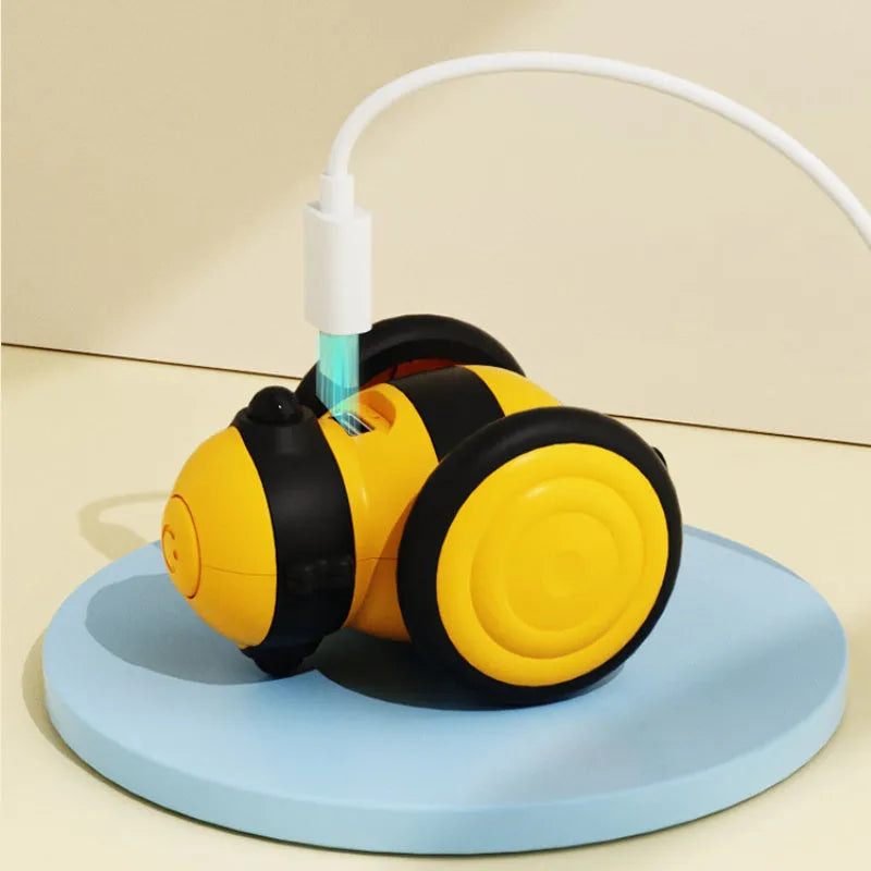 Pink and yellow bee-themed electric cat toy with feather attachment on floor