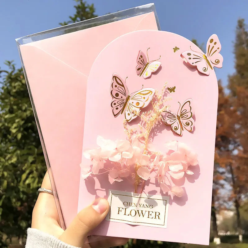 Handmade 3D boxed greeting card with butterfly shape, hot stamping, and artificial flowers on coated paper.