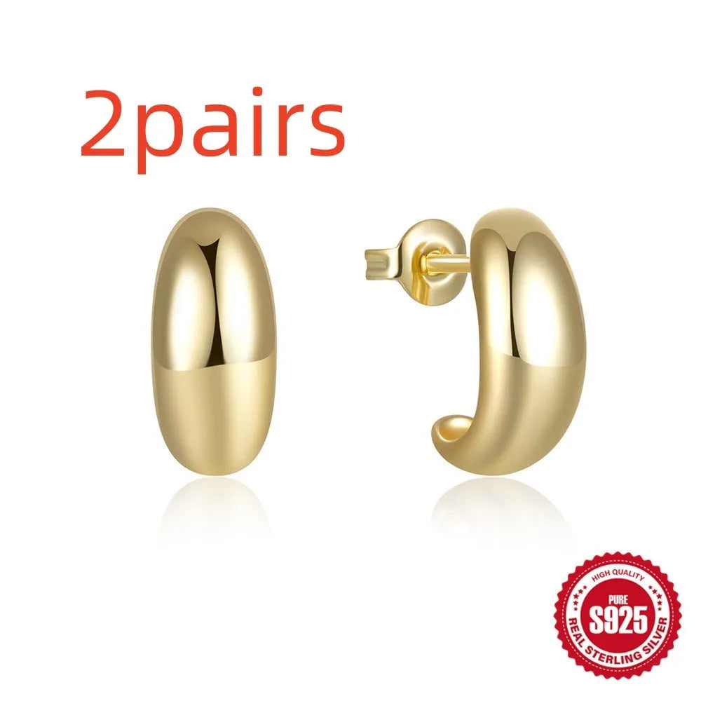 Close-up of a glossy C-shaped sterling silver stud earring with a post back, shown on a neutral background.