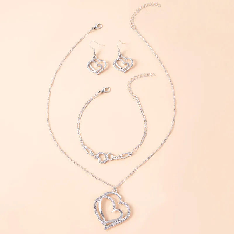 Silver romantic crystal heart jewelry set with bracelet necklace earrings on white background