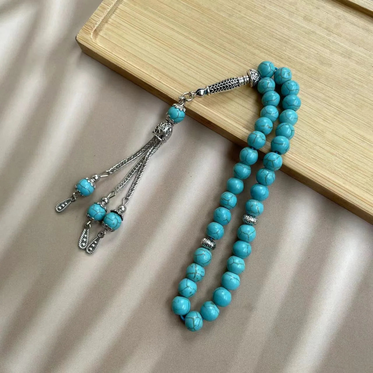 Sky blue stone bead Muslim prayer bracelet with sliding knot on a wrist.