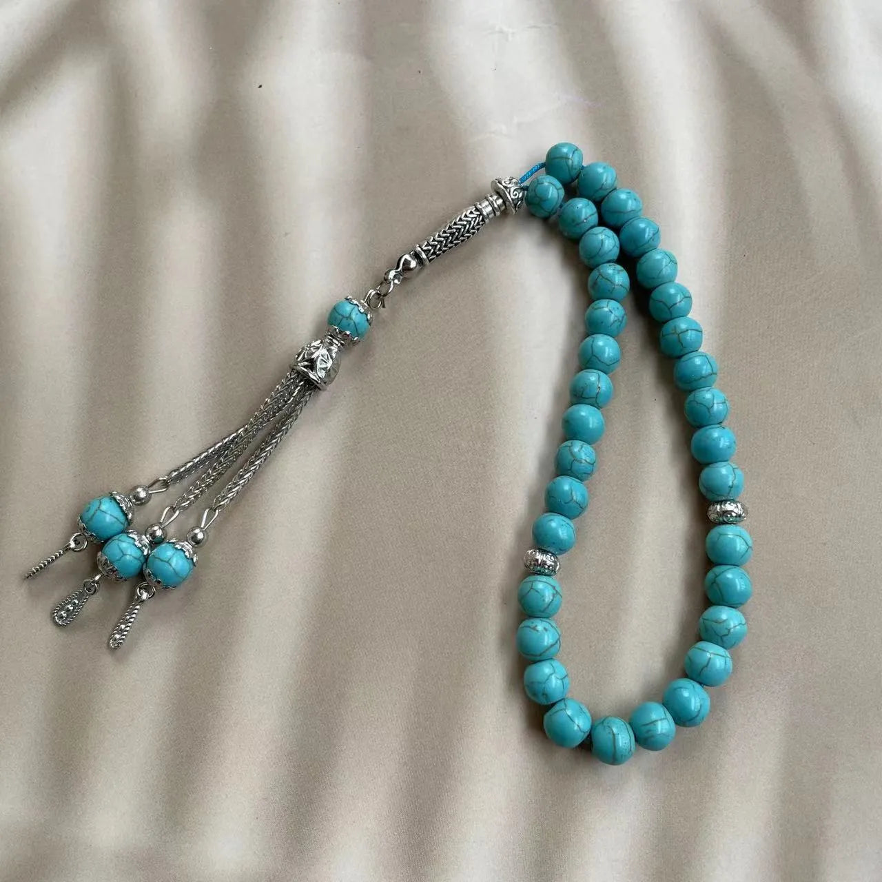 Sky blue stone bead Muslim prayer bracelet with sliding knot on a wrist.