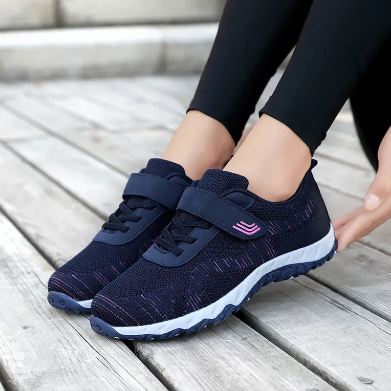 Women's grey purple wedge shoe with Velcro strap and mesh upper on a solid colour background.
