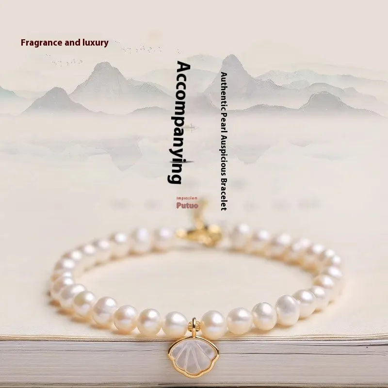Close-up of a women's freshwater pearl fan bracelet on a wrist, showing elastic string and chain fastening options.