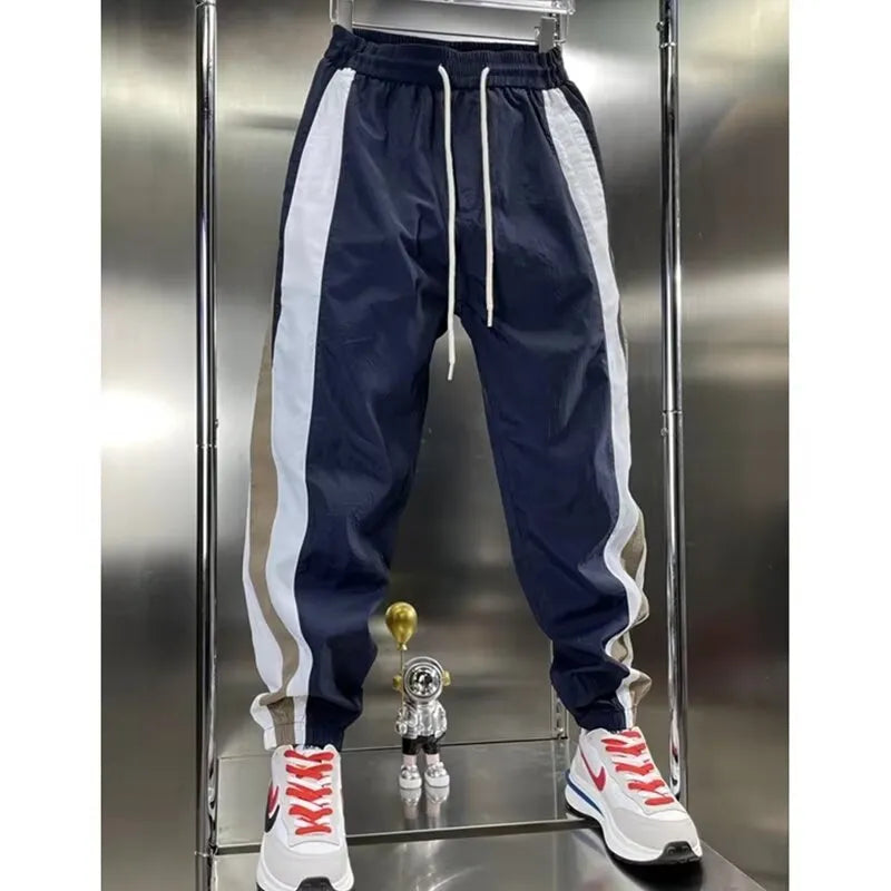 Men's loose fit contrast stripe jogger sports pants in black, showing drawstring waist and tapered leg