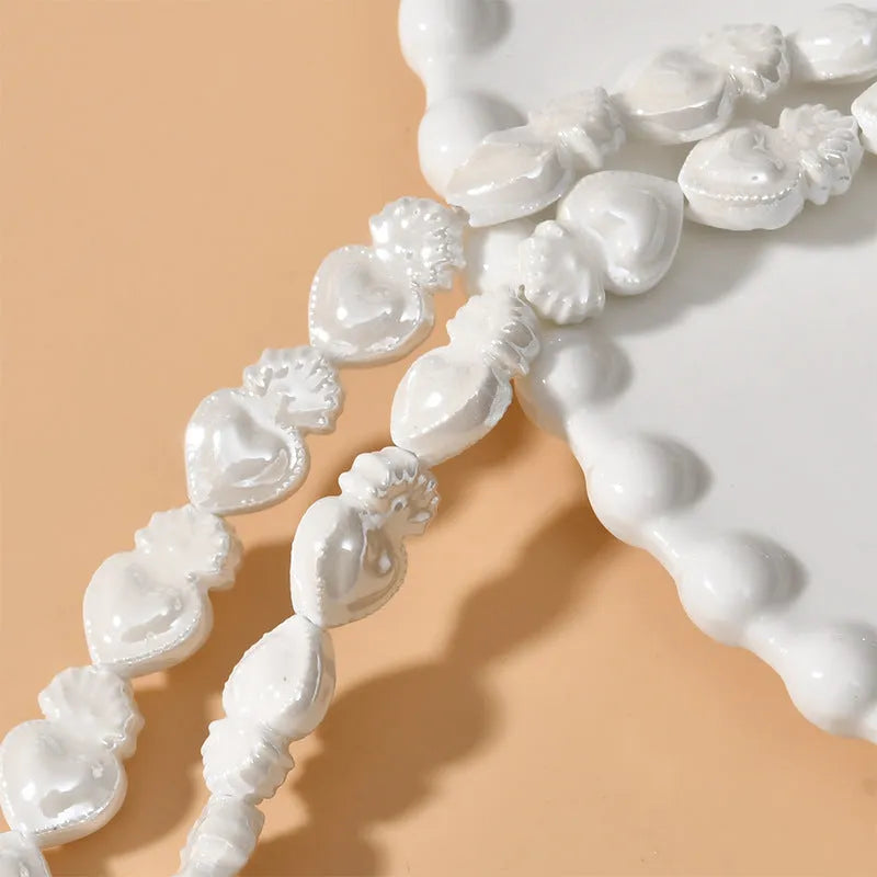 Assorted small ceramic torch beads in multiple colours on a white background.
