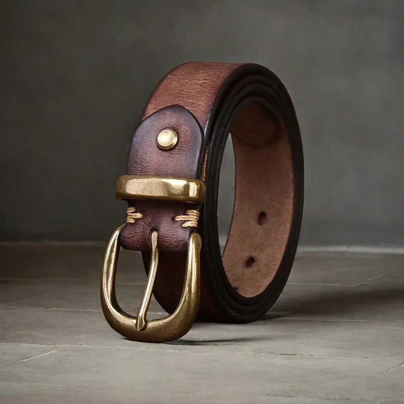 Men's black cattlehide leather belt with a copper pin buckle on a jeans background.