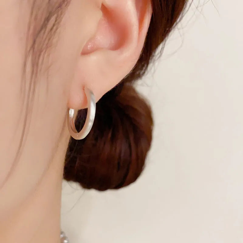 A pair of geometric round eyelet ear clips for women in gold or silver plating.