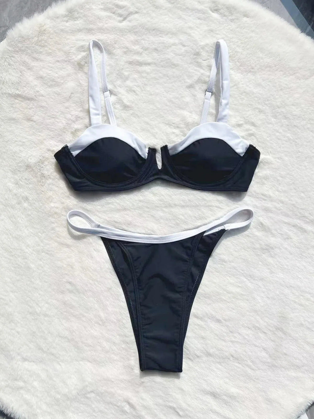 Women's black low waist bikini swimsuit with stitching split detail on mannequin