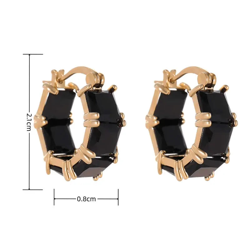 A pair of geometric U-shaped gold ear rings with round details and black zircon crystals.