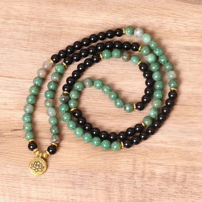 Green and black elastic beaded alloy bracelet on a wrist.