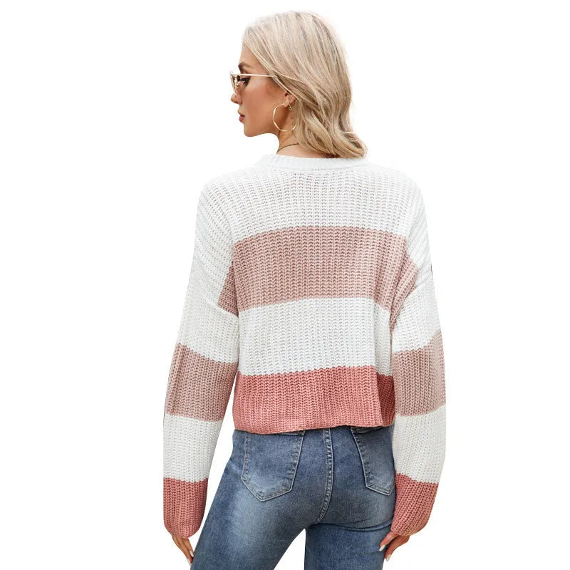 Woman wearing a short loose striped acrylic pullover sweater in a pink stripe variant.