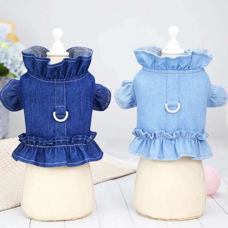 Blue denim dog dress with ruffle trim and metal leash attachment rings on chest and back