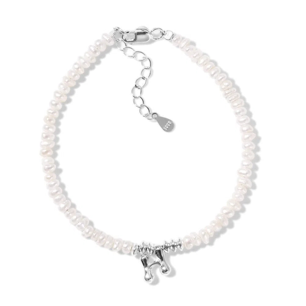 Women's natural freshwater pearl bracelet in 925 silver with letter shape charm on neutral background