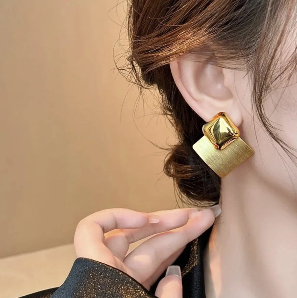 Women's gold brushed square stud earrings with 925 silver needle posts on a light background