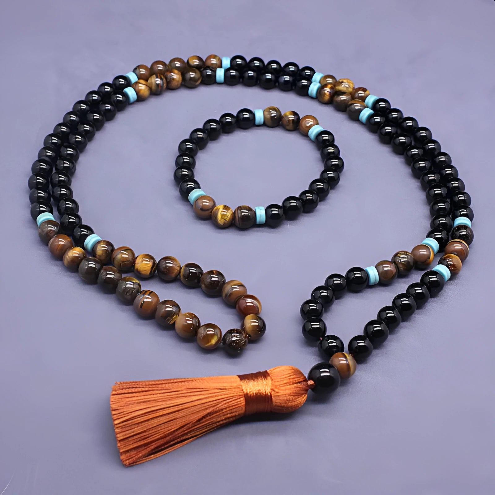 Black agate geometric bead bracelet and matching tiger-shaped tigereye stone necklace set on a grey background.