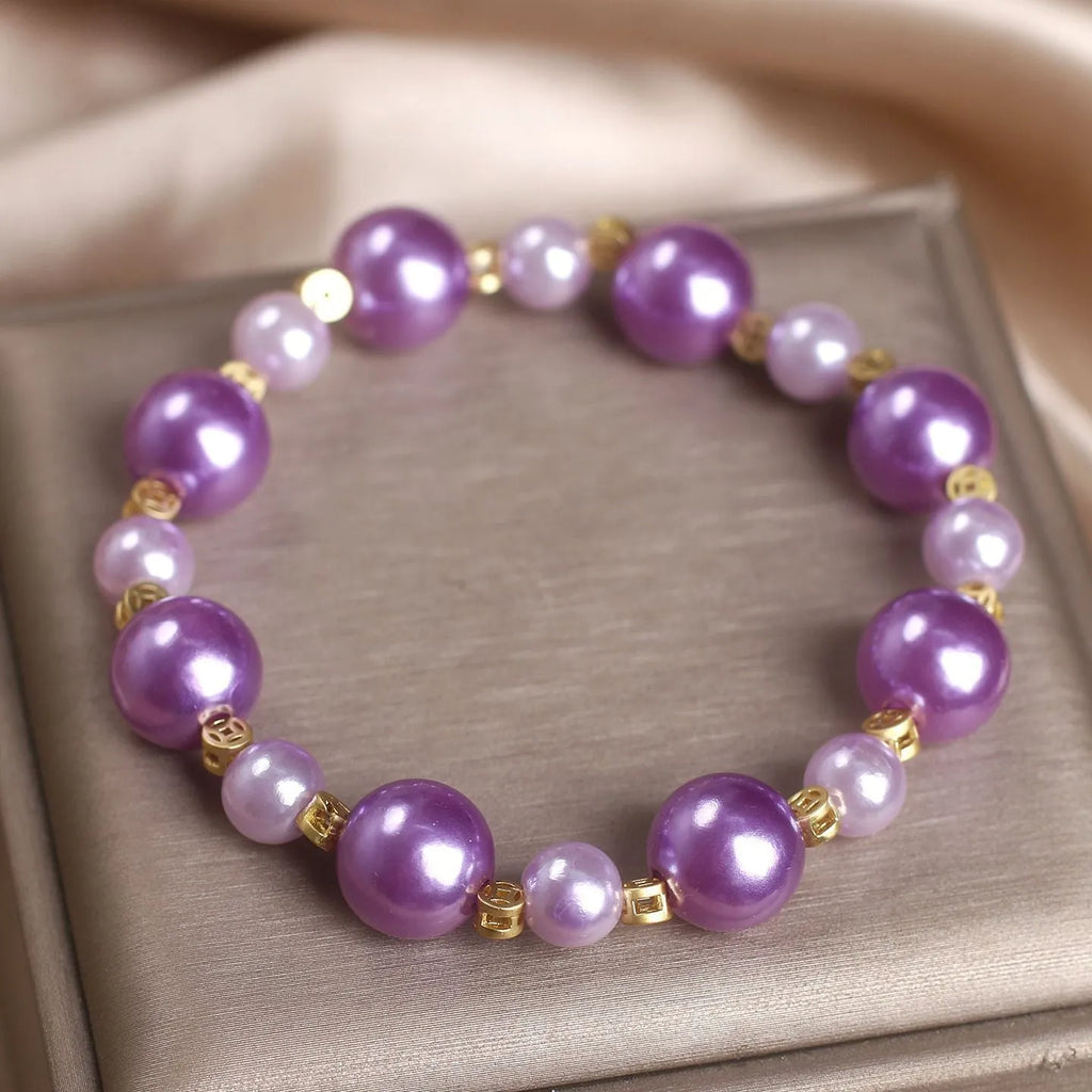 Purple shell pearl bracelet with letter coin accent on white background