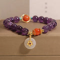 Natural amethyst bracelet with sliding knot and small flower inlay on a white background