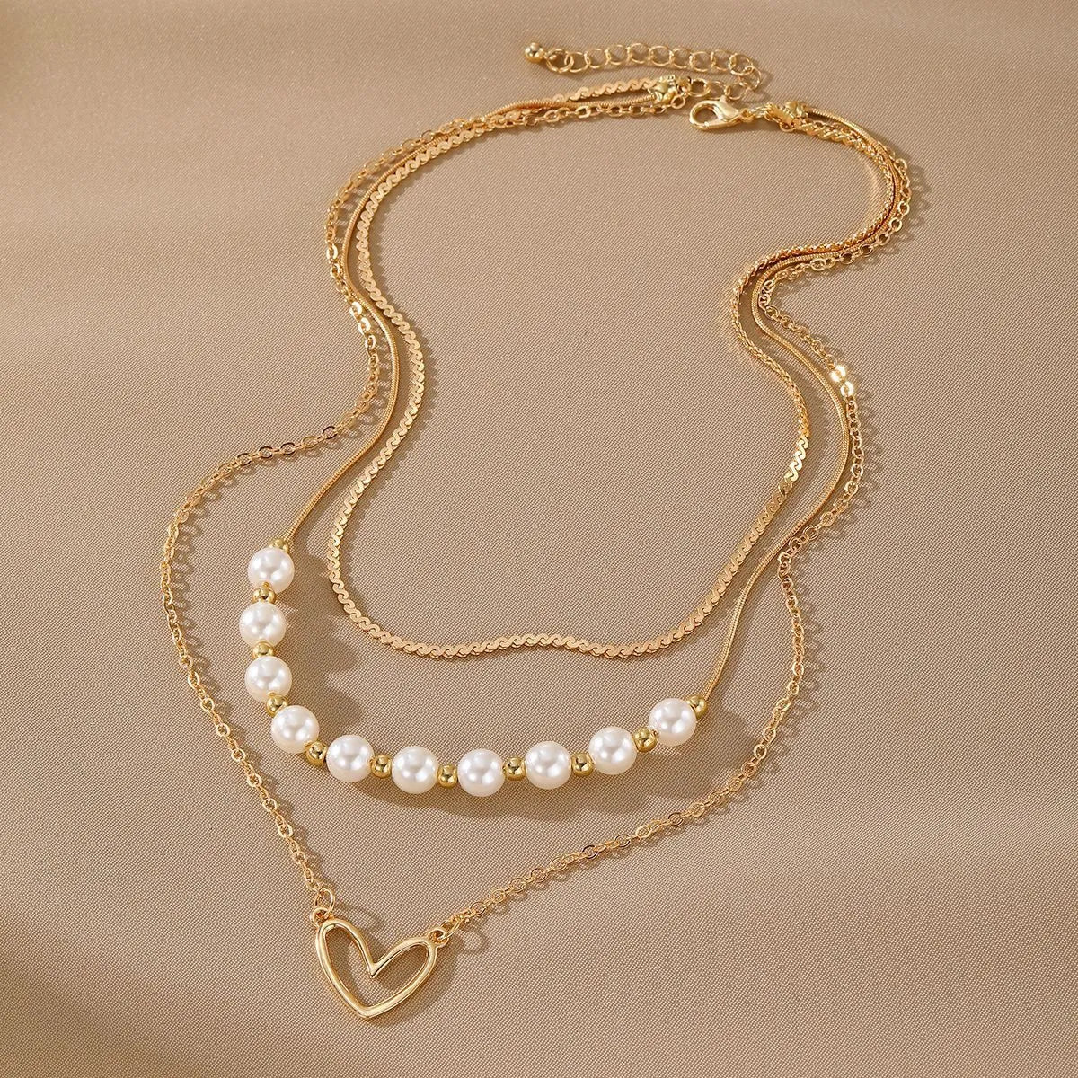 Vintage gold necklace with heart pendant on adjustable pearl chain, showing electroplated finish and love motifs
