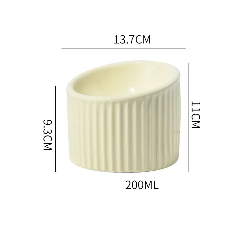 Ceramic elevated cat bowl in light green, showing its tilted, round shape and raised design on a table.