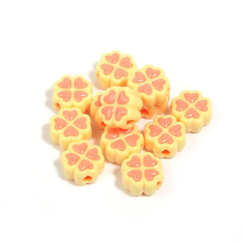A selection of 15mm frosted acrylic beads showing a raised cartoon love and four-leaf clover pattern in various colours.