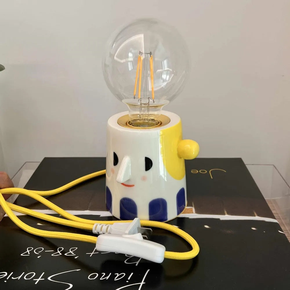 Handmade ceramic bedside lamp with ball headlight colour design on a table.