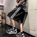 Men's black loose-fit track pants with elastic waistband and baggy leg silhouette