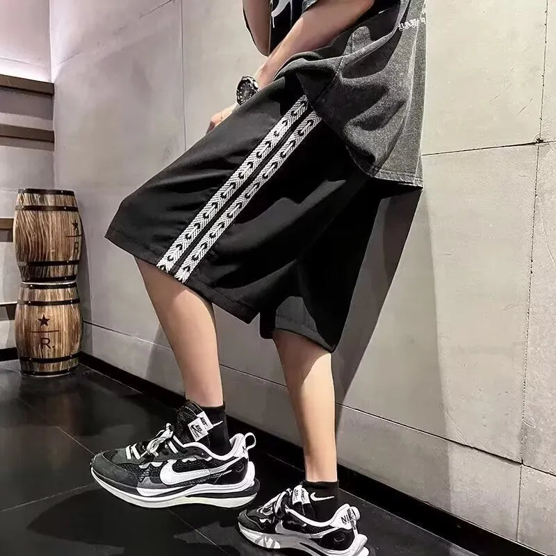 Men's black loose-fit track pants with elastic waistband and baggy leg silhouette