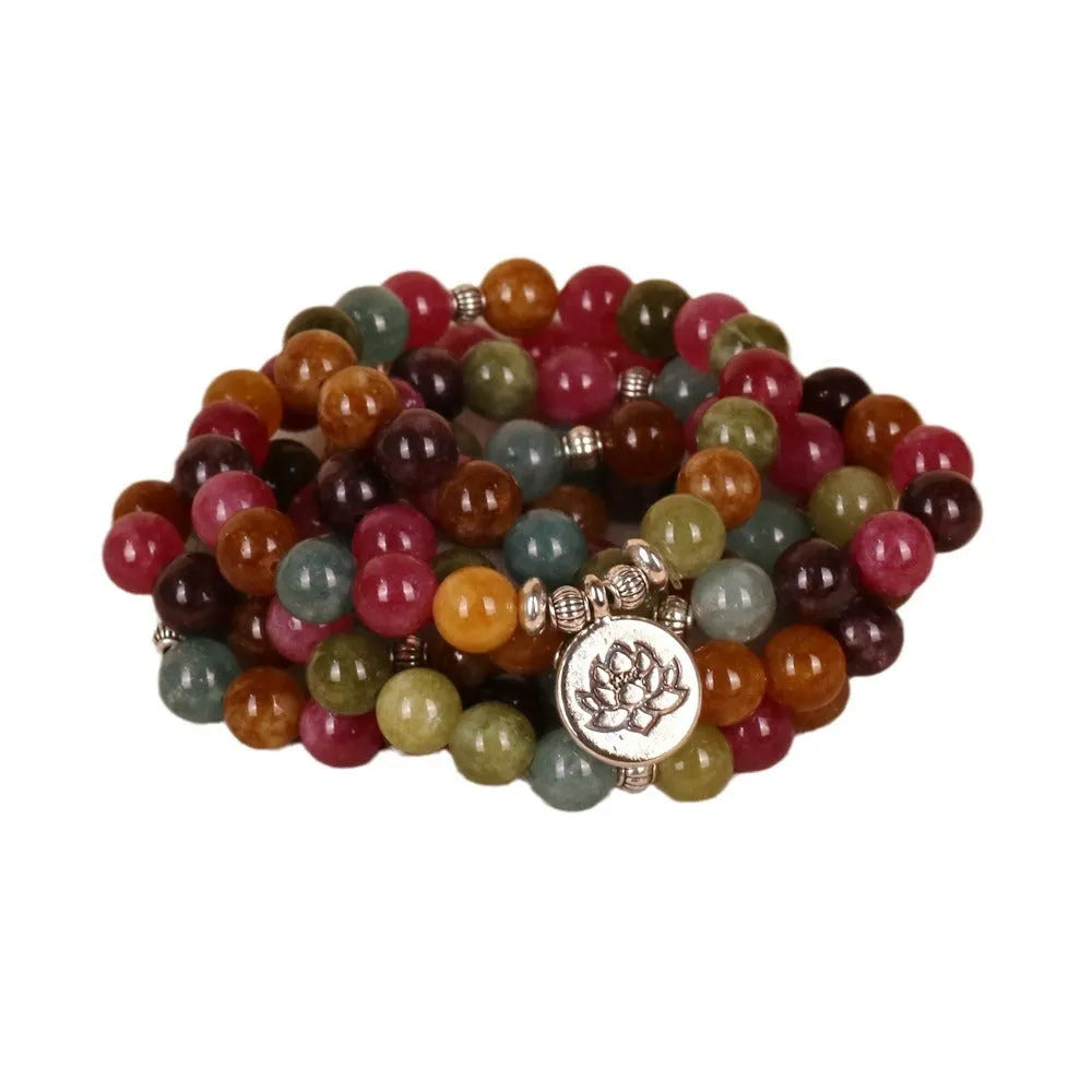 Close-up of a multi-layer beaded bracelet with 108 alloy beads and a central lotus pendant in a tourmaline colour.