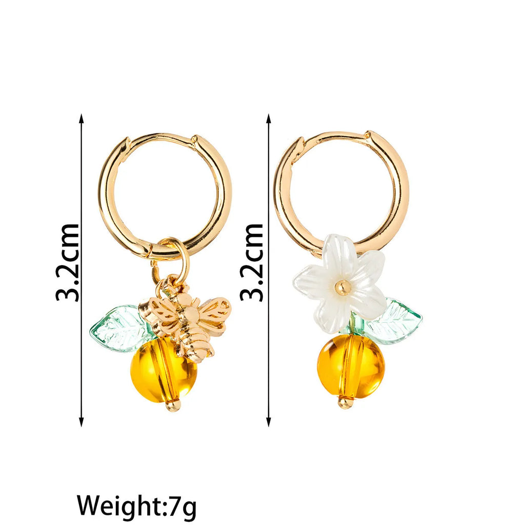 Pair of yellow acrylic sweet bee and honey fruit shaped earrings on a white background