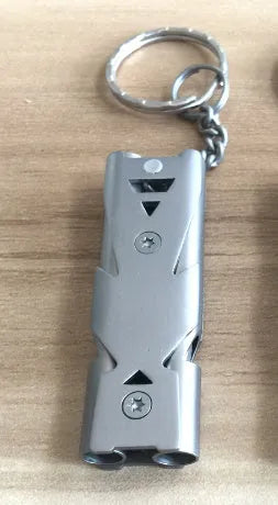 Keychain whistle in black with metal lanyard ring on a plain background