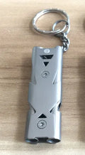 Keychain whistle in black with metal lanyard ring on a plain background