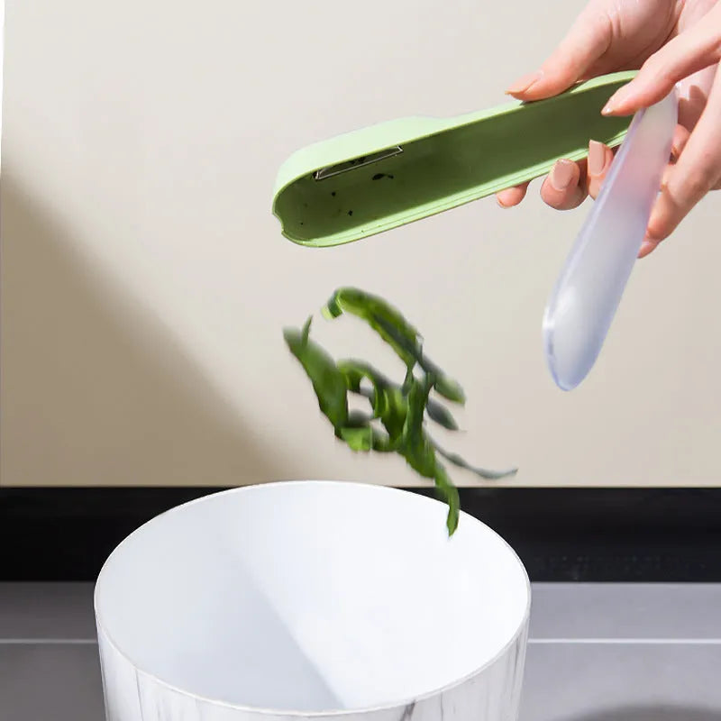 Dark green vegetable peeler with a storage tube and stainless steel blade on a kitchen counter.