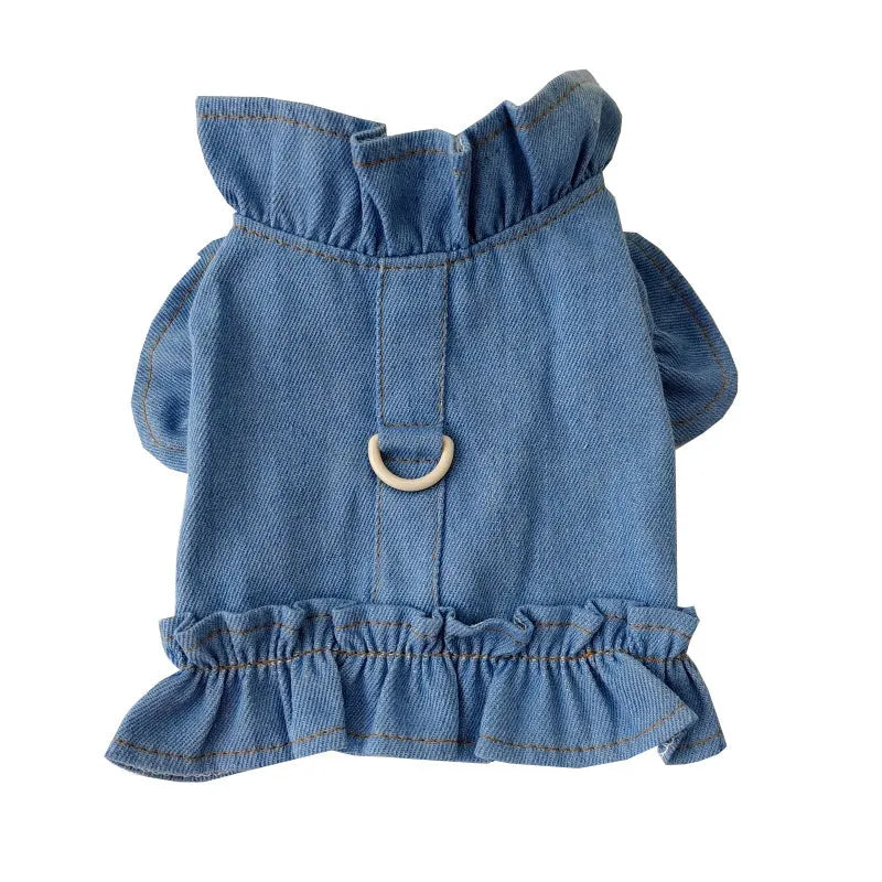 Blue denim dog dress with ruffle trim and metal leash attachment rings on chest and back