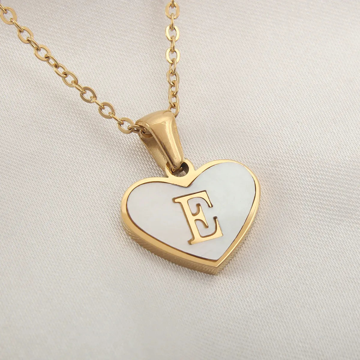 Gold plated heart-shaped necklace with a personalised initial letter and white shell detail on a 50cm adjustable chain.