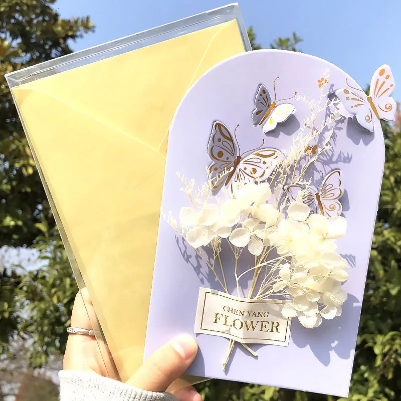 Handmade 3D boxed greeting card with butterfly shape, hot stamping, and artificial flowers on coated paper.