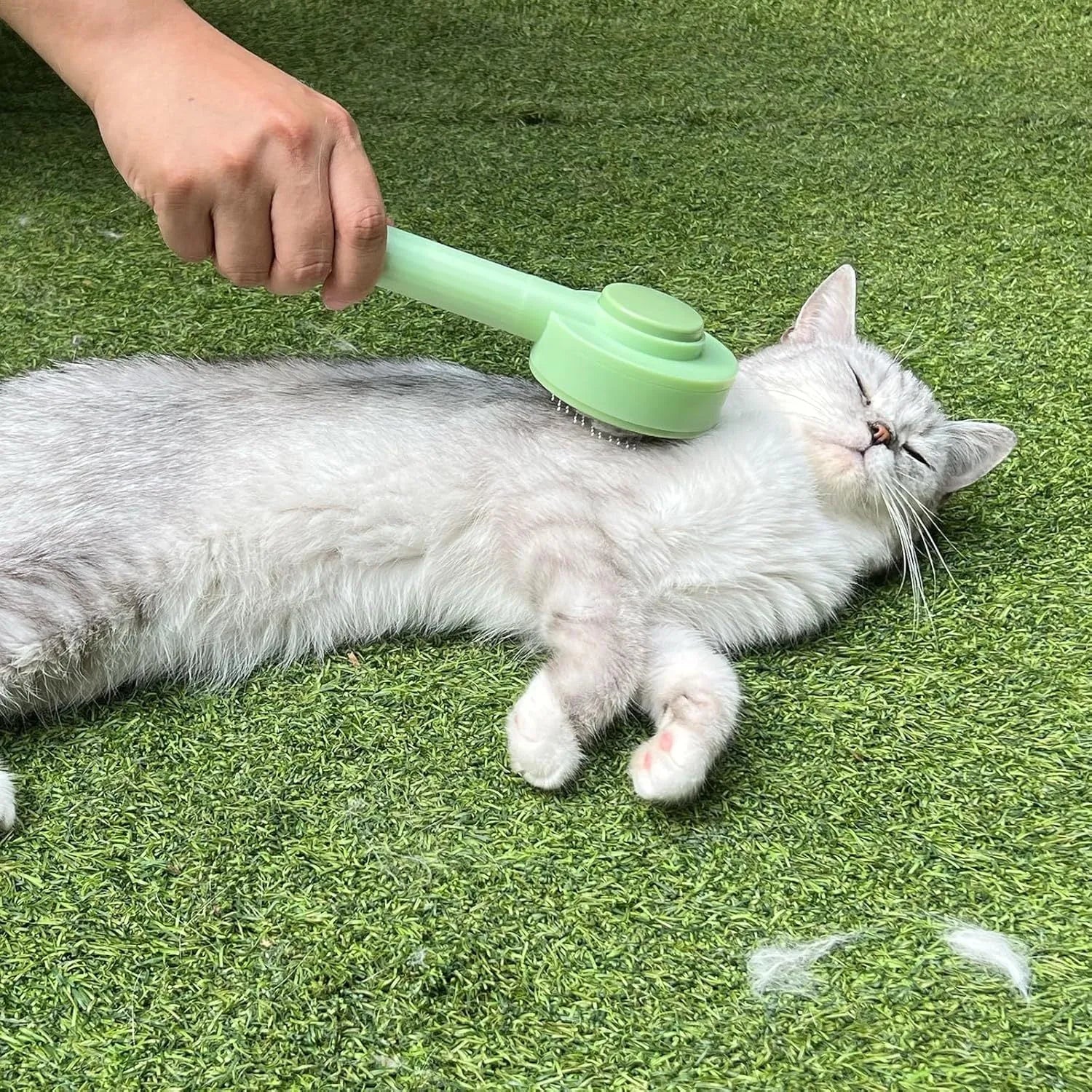 Green and yellow 2-in-1 pet grooming brush with stainless steel teeth and a hanging loop for storage.