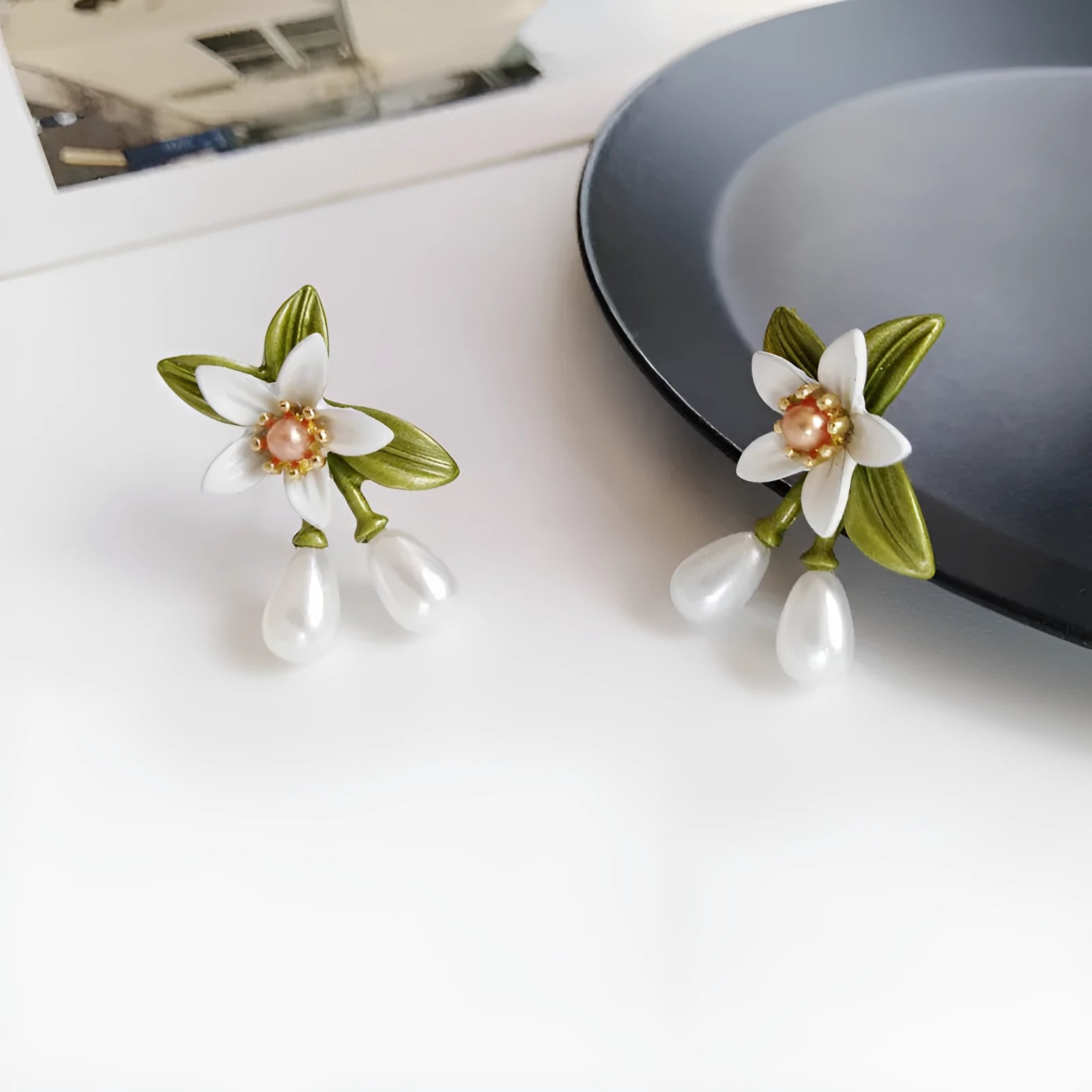 A pair of alloy camellia flower earrings for women, showing both the stud and clip styles.