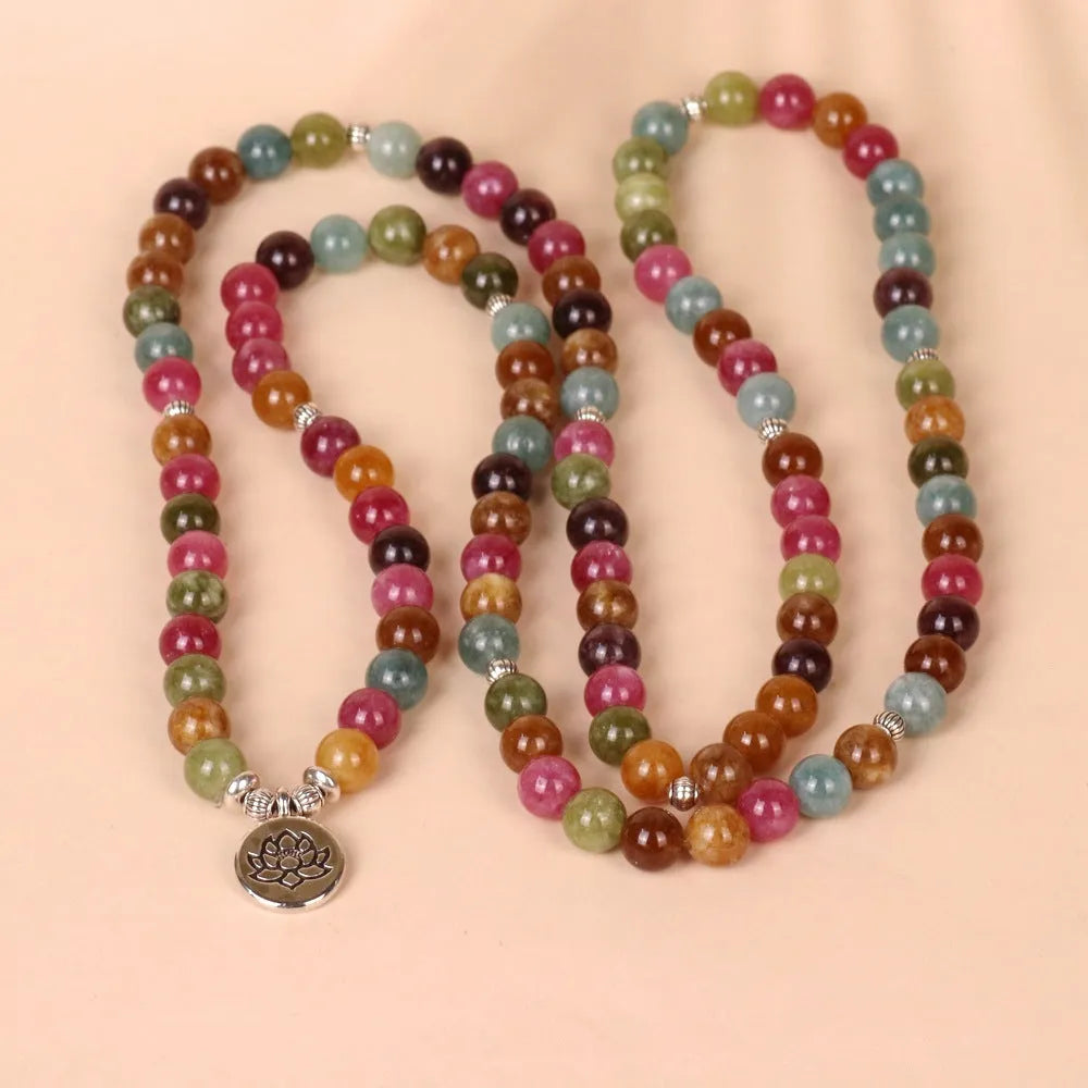 Close-up of a multi-layer beaded bracelet with 108 alloy beads and a central lotus pendant in a tourmaline colour.