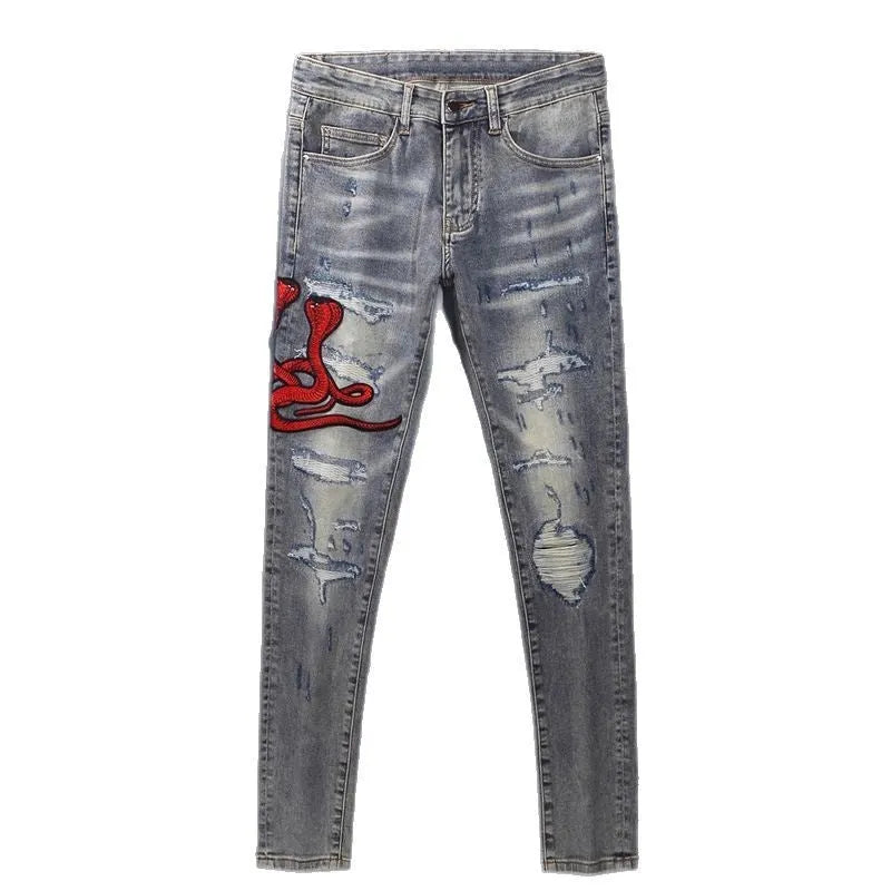 Slim fit light blue jeans with distressed knee patches, embroidery detail, and a faded wash.