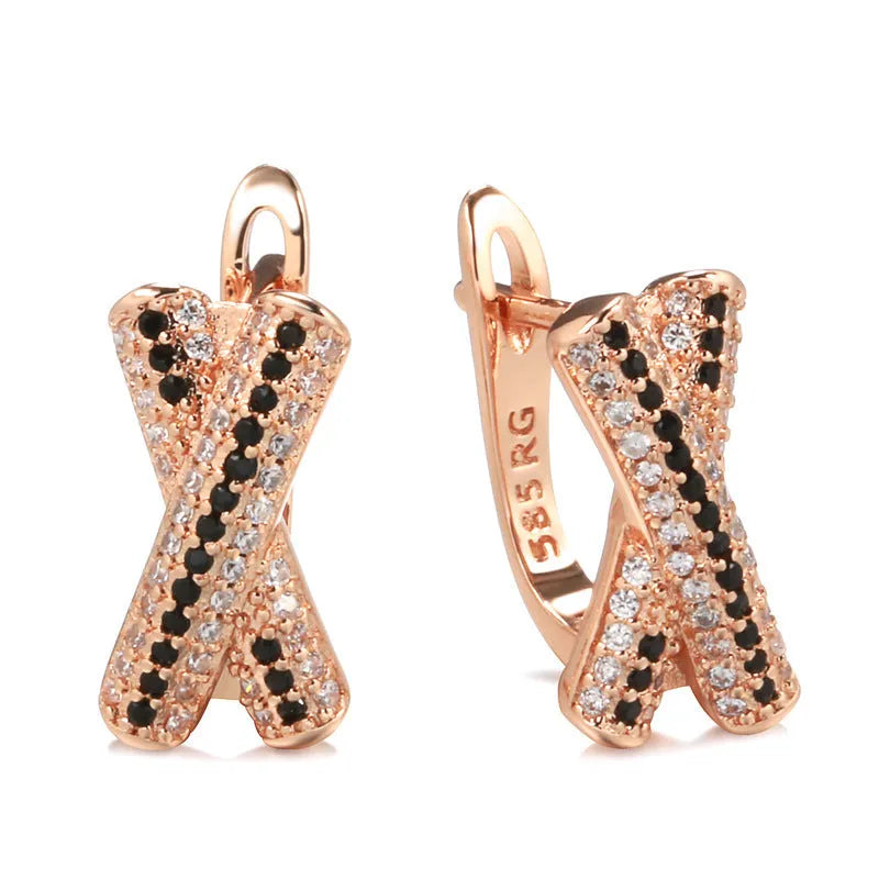Pair of rose gold copper earrings with hollow-out X-shaped geometric design on light background