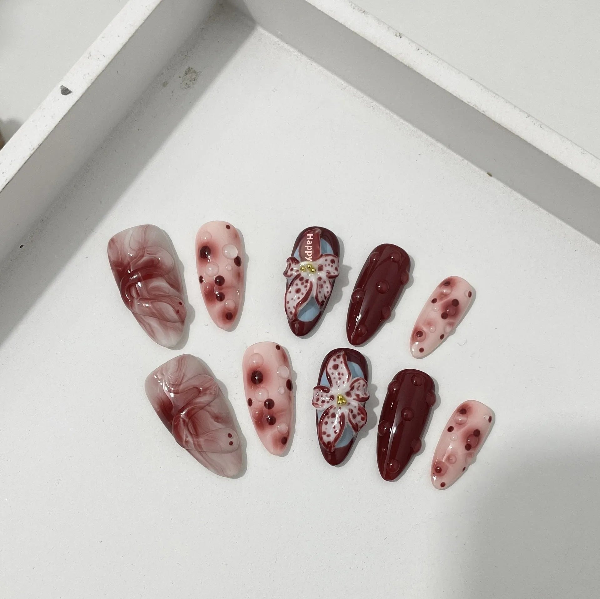 Hand-painted three-dimensional carved acrylic manicure nails in almond colour with floral and geometric patterns
