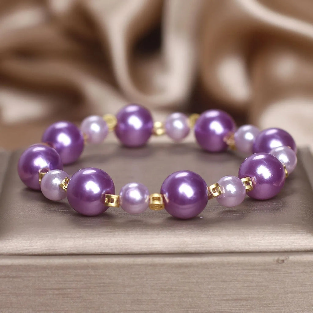 Purple shell pearl bracelet with letter coin accent on white background