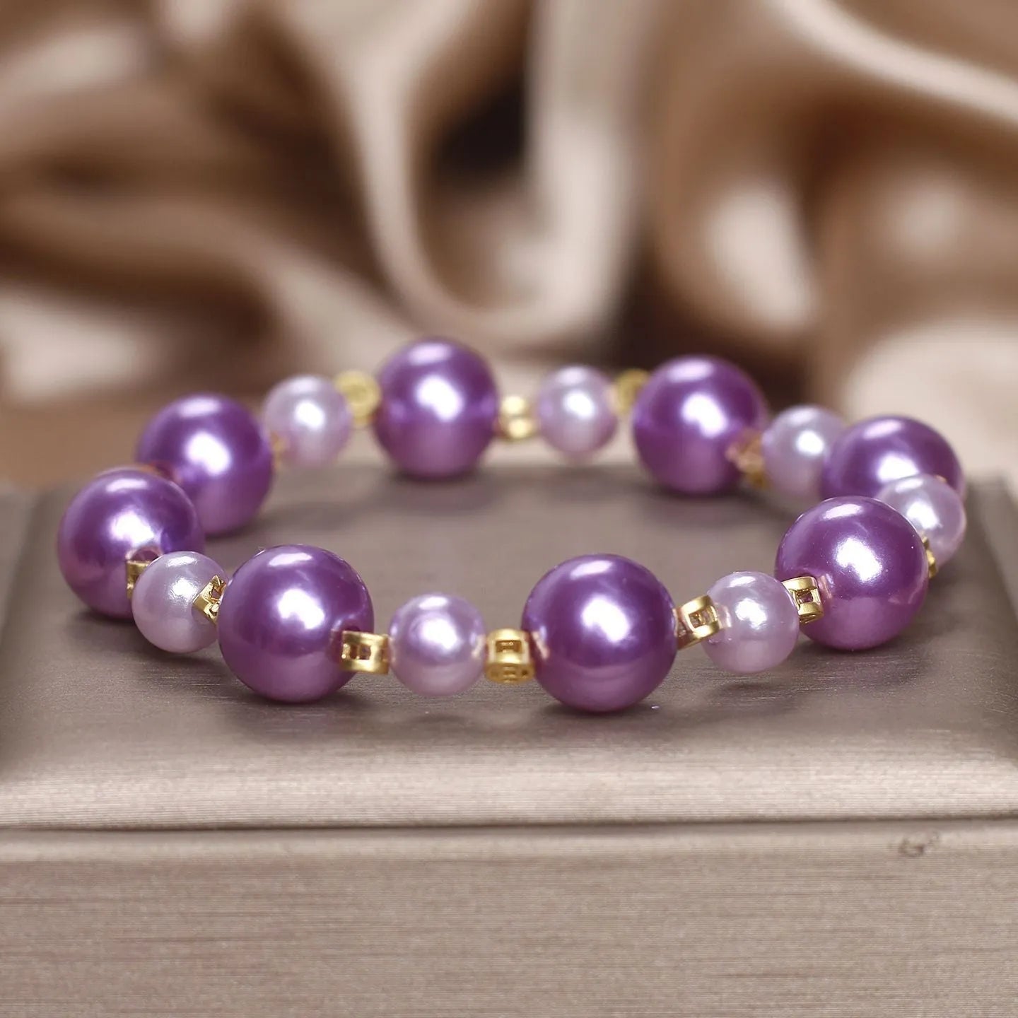 Purple shell pearl bracelet with letter coin accent on white background