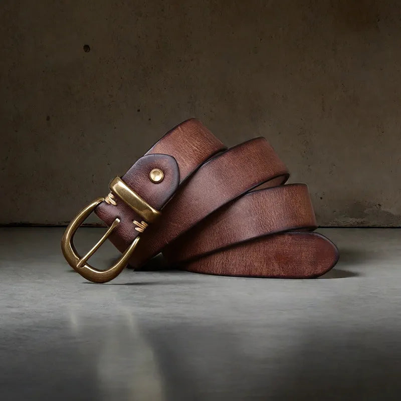 Men's black cattlehide leather belt with a copper pin buckle on a jeans background.