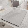 Square diatomite kitchen draining mat in camellia purple on a kitchen worktop, with a teacup resting on it
